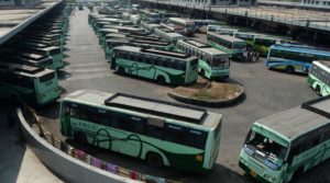 Indian travellers stand next to buses parked at a depot during a transport strike in Chennai on January 5, 2018. The Tamil Nadu State Transport Corporation is on an indefinite strike as employees seek a wage hike, stranding thousands of travellers in the southern Indian state. / AFP PHOTO / ARUN SANKAR