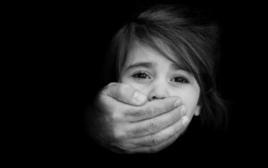 Strong male hands cover little girl face with emotional stress, pain, afraid, call for help, struggle, terrified expression.Concept Photo of abduction, missing, kidnapped,victim, hostage, abused child