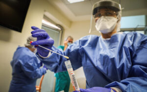 Hadassah Ein Kerem medical team members, wearing protective gear, are handling a Coronavirus test sample of Hadassah Ein Kerem workers at the Hadassah Ein Kerem Hospital in Jerusalem on March 24, 2020. Photo by Yossi Zamir/Flash90 *** Local Caption *** קורונה וירוס מגיפה מגן דוד אדום צוות רפואי הצלה בדיקות נשאים הדסה עין כרם